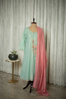 A dress on a mannequin in front of a curtain