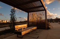 A wooden bench sitting under a metal roof