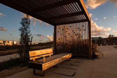 A wooden bench sitting under a metal roof