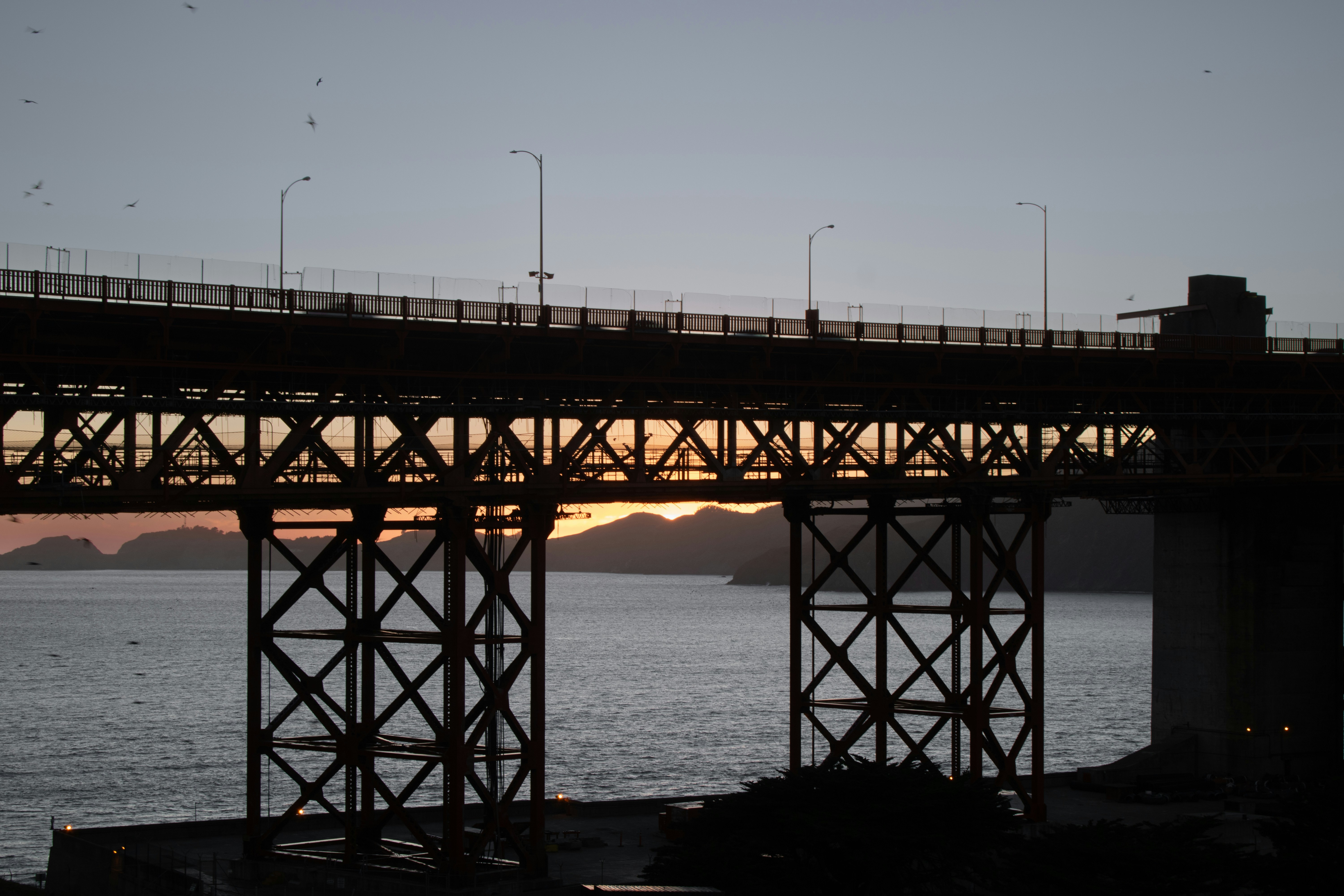 A bridge over a body of water at sunset, The view of the start of the Golden Gate Bridge from Presidio