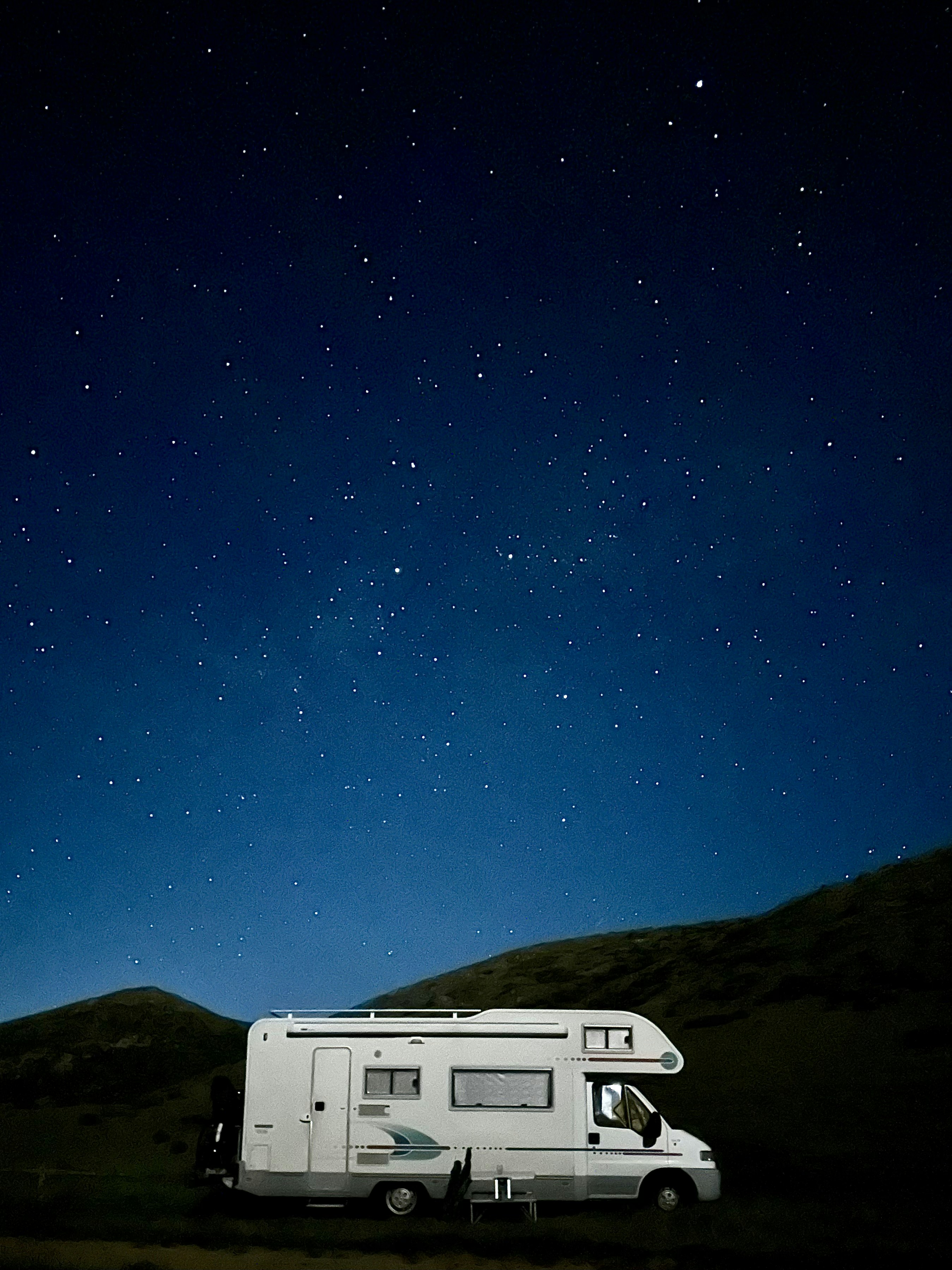 A camper parked in a field under a night sky