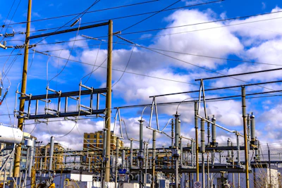 A train traveling past a power plant under a cloudy blue sky