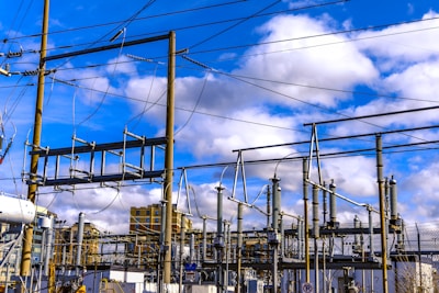 A train traveling past a power plant under a cloudy blue sky