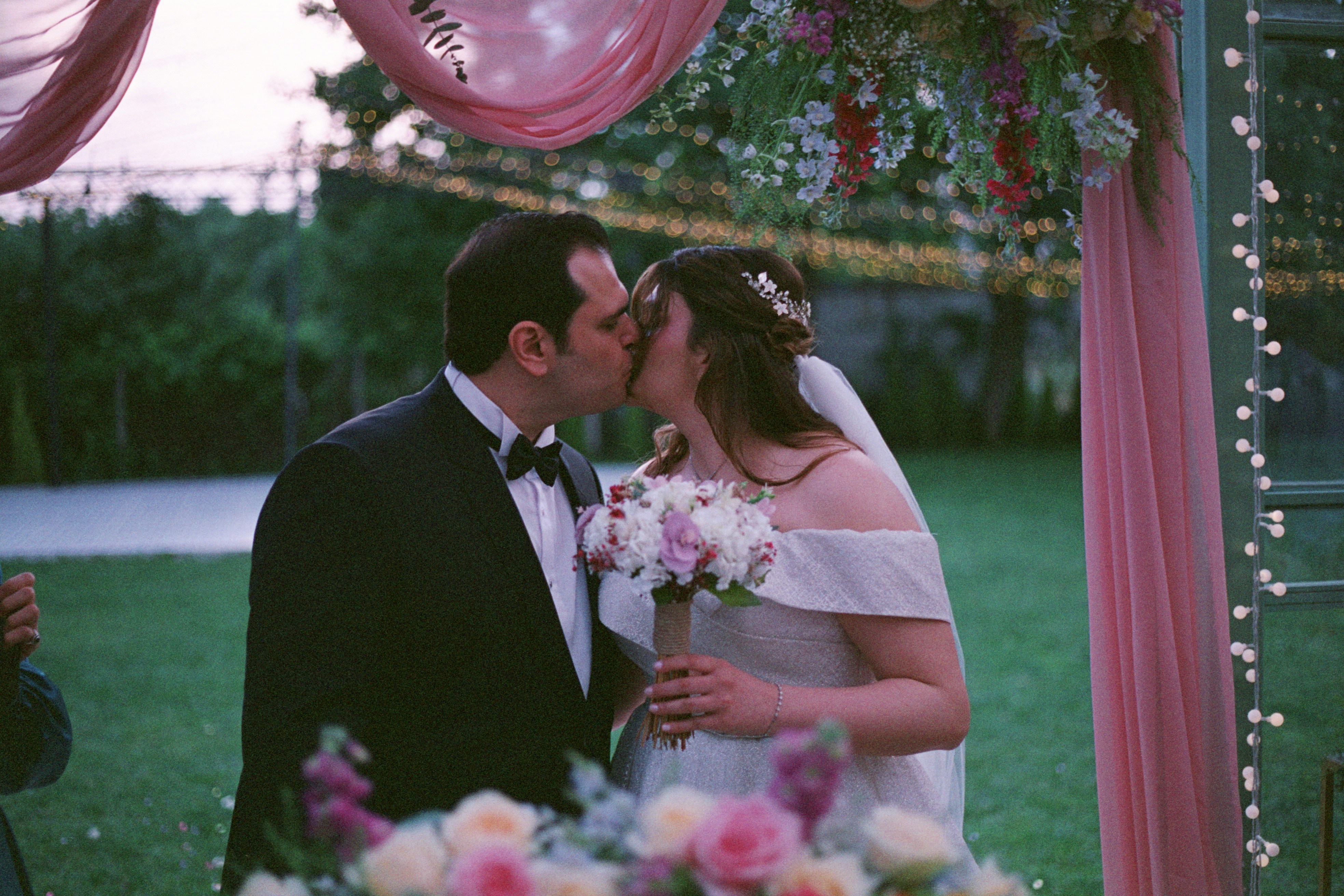 A bride and groom kissing under a wedding arch