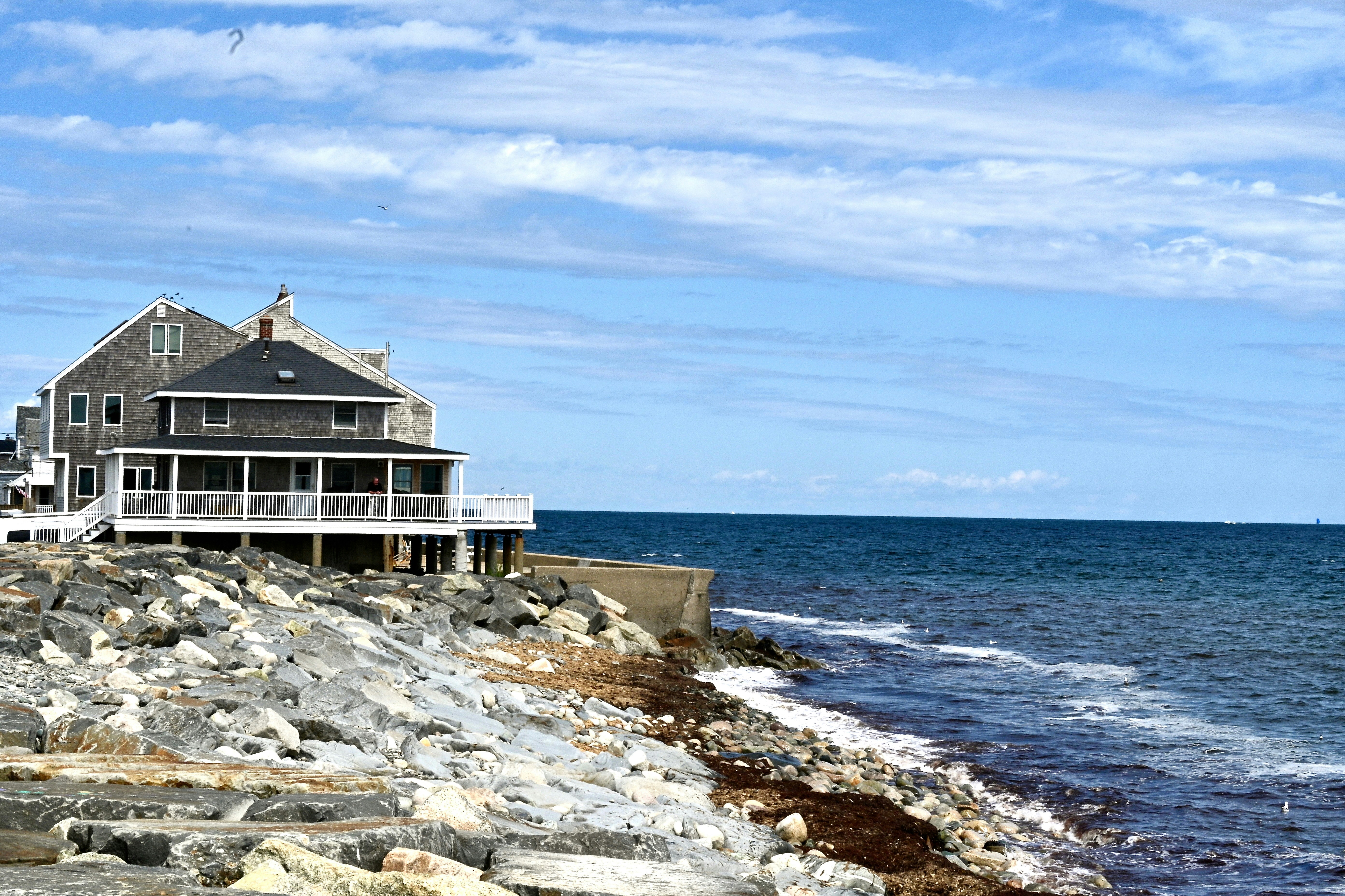 A house sitting on top of a rocky cliff next to the ocean