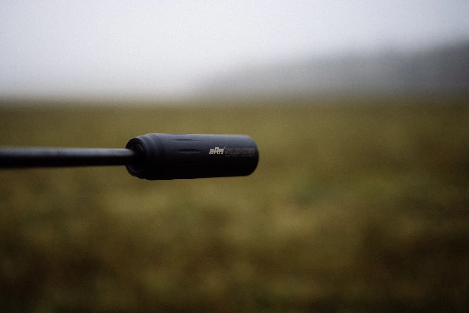 A long, thin shotgun microphone pointing out across a misty field