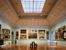 A room filled with lots of paintings and a skylight