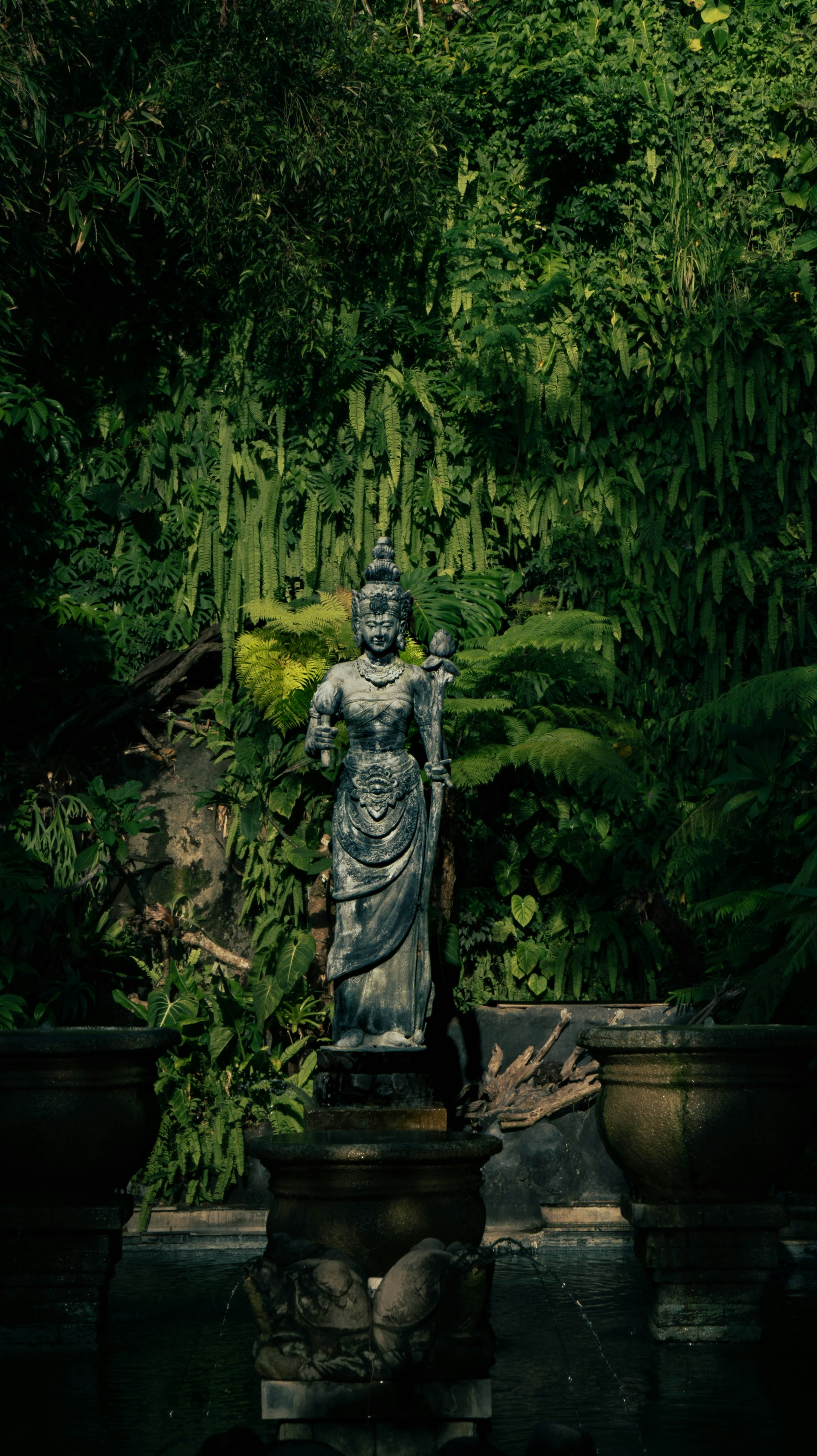 A statue in a garden surrounded by plants