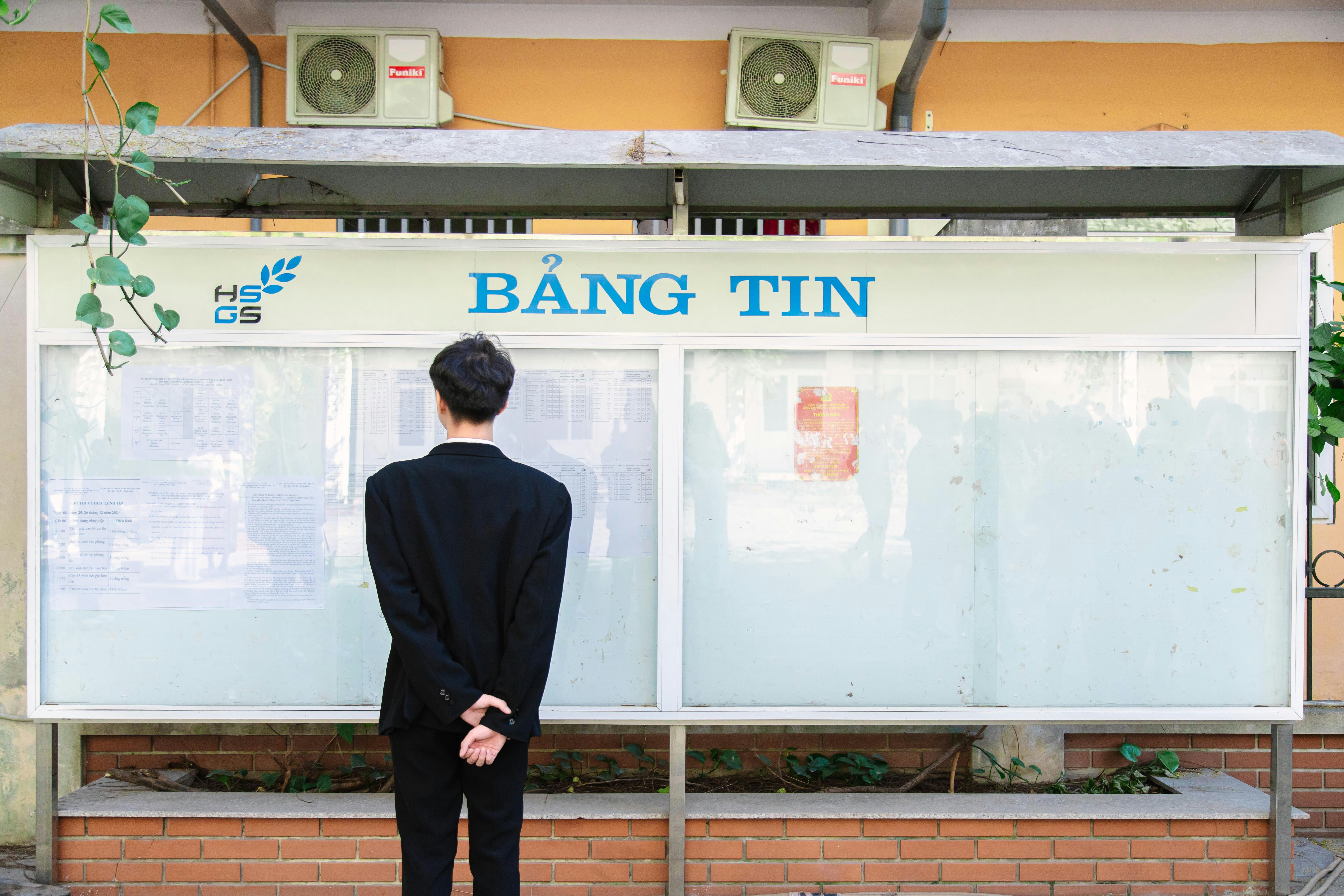 A man in a suit standing in front of a sign
