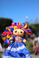 A small mexican doll with a blue dress and colorful hair