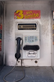 An old style pay phone in front of a wall