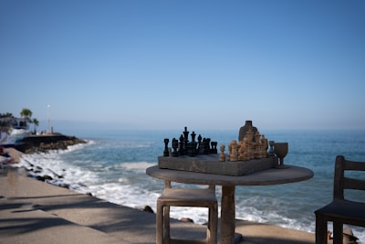 A table with a chess set on top of it next to the ocean