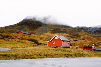 A red house on a hill with mountains in the background