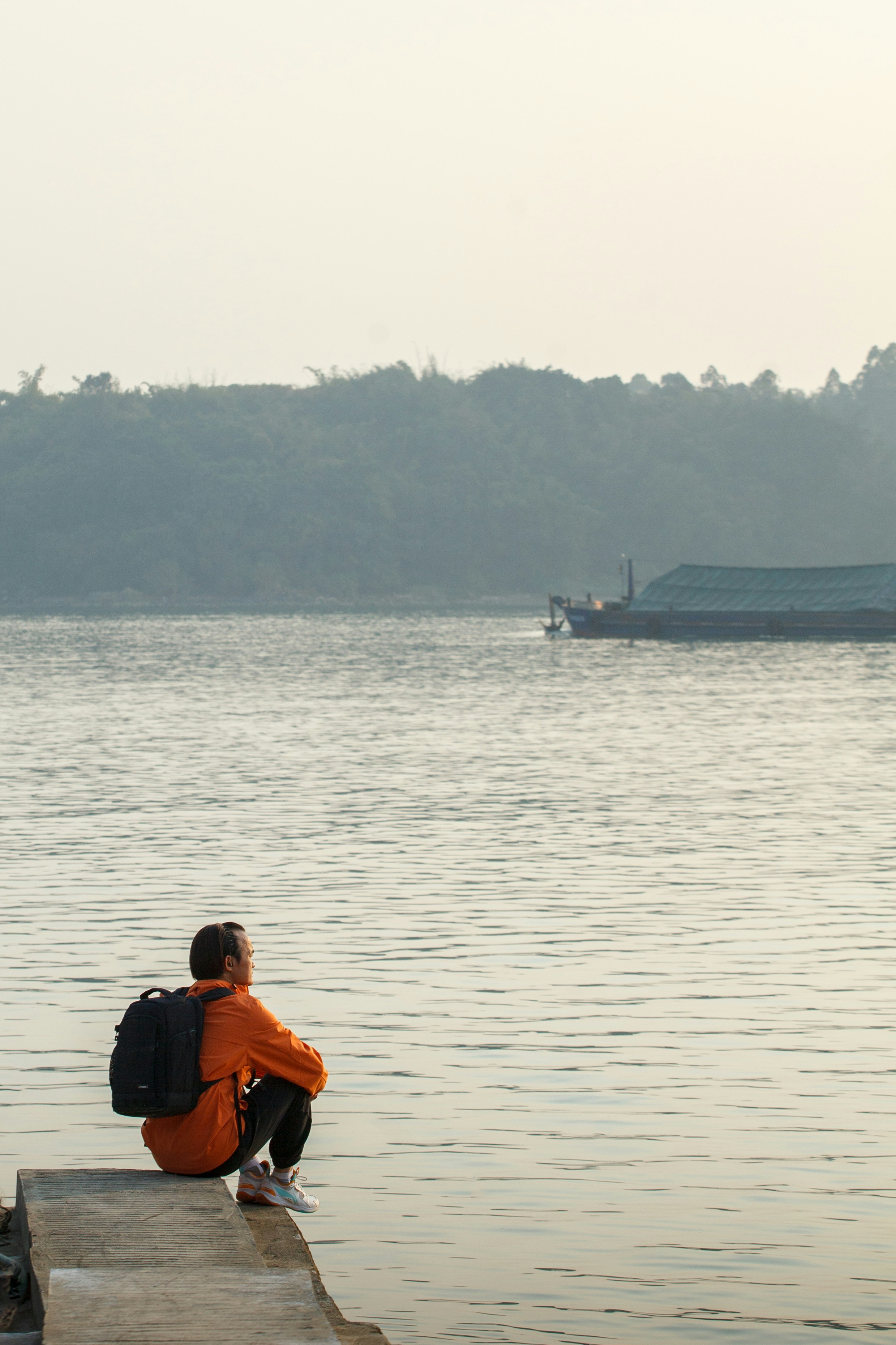 A person sitting on a dock looking out at the water photo – Free Land ...