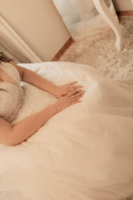 A woman laying on a bed in a white dress