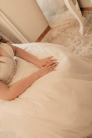 A woman laying on a bed in a white dress