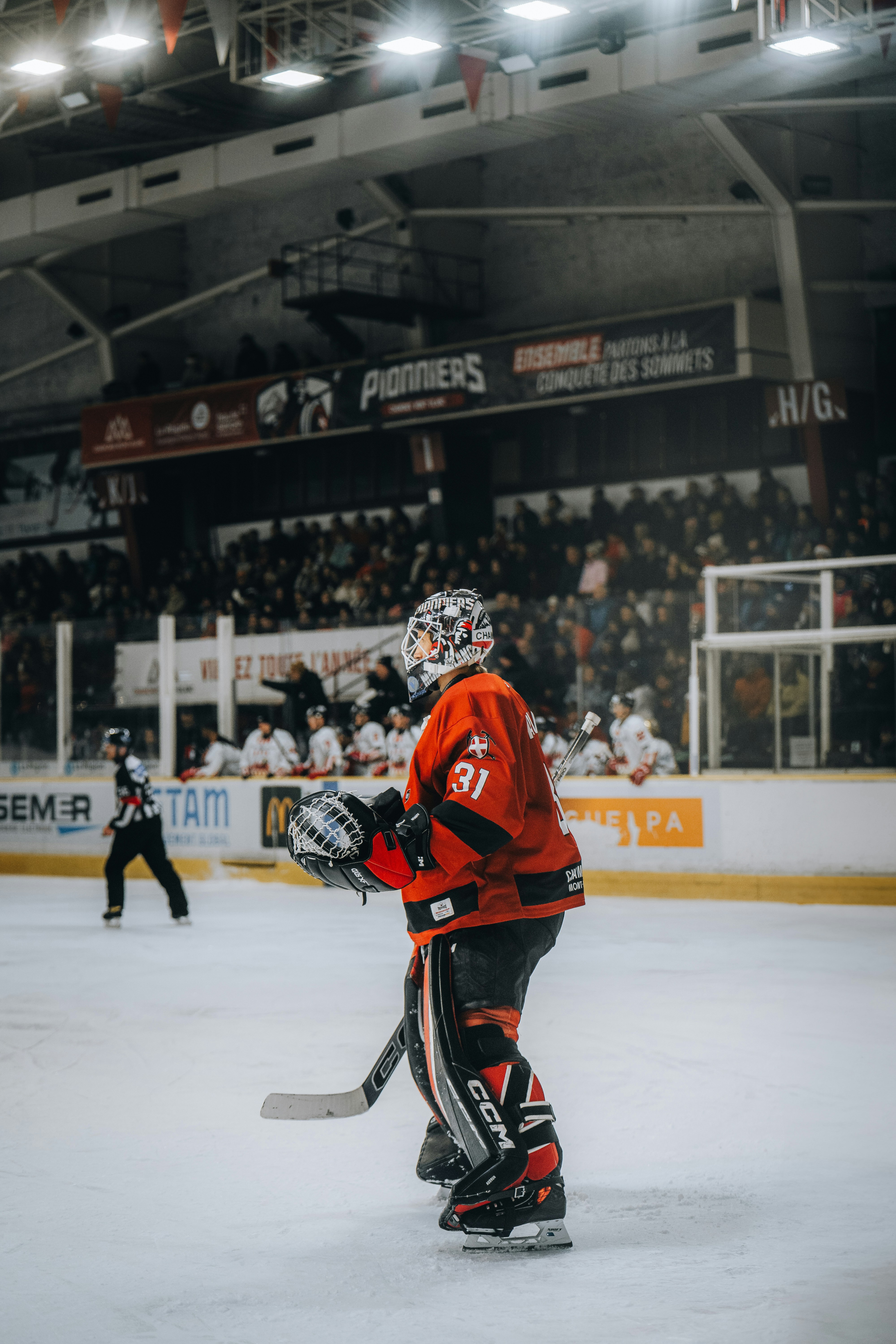 A hockey player skating on fresh ice under arena lights during a professional game
