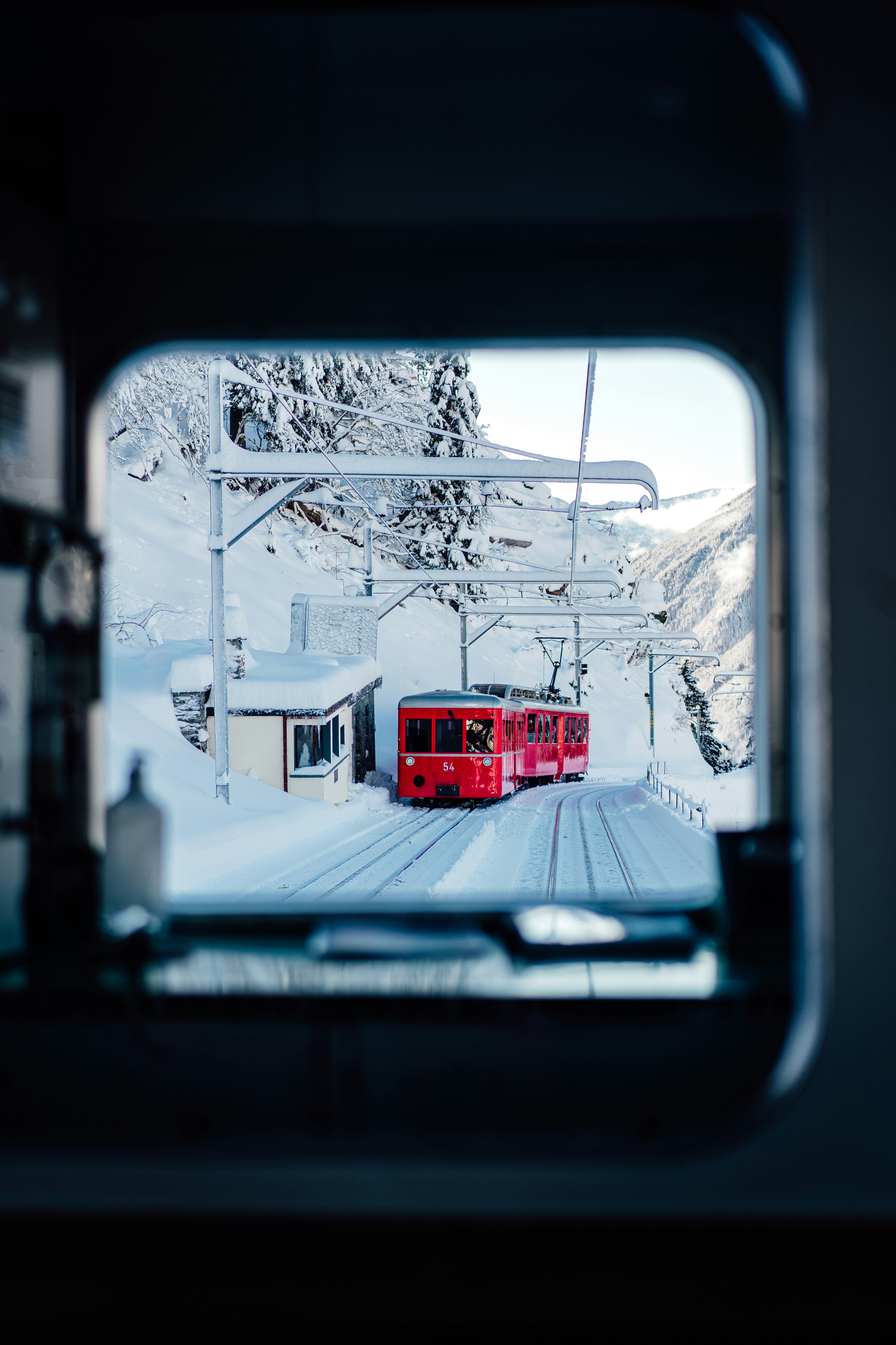 A red train traveling down train tracks next to a snow covered mountain