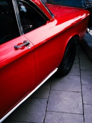A red car is parked on the side of the road