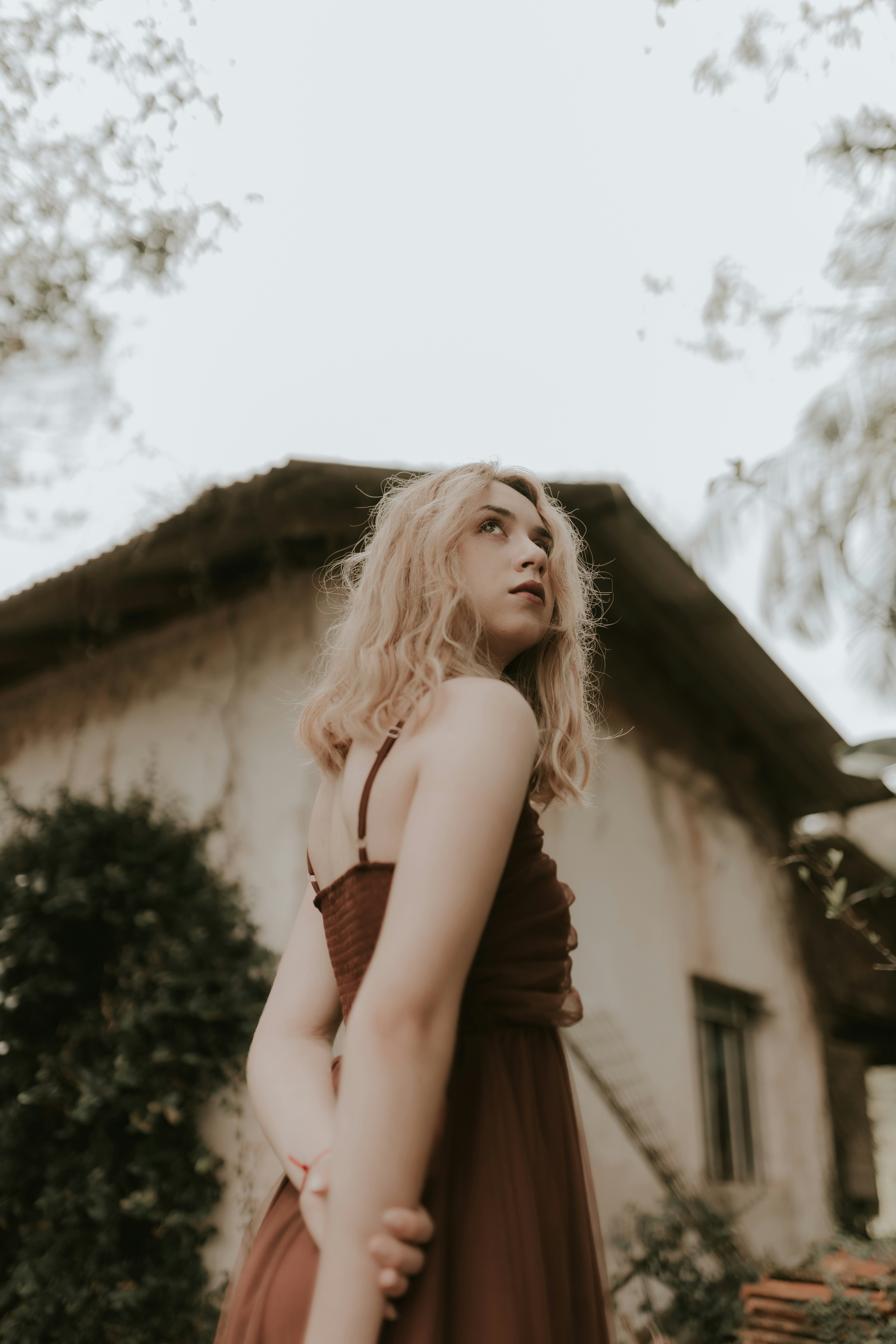 A woman in a brown dress standing in front of a house
