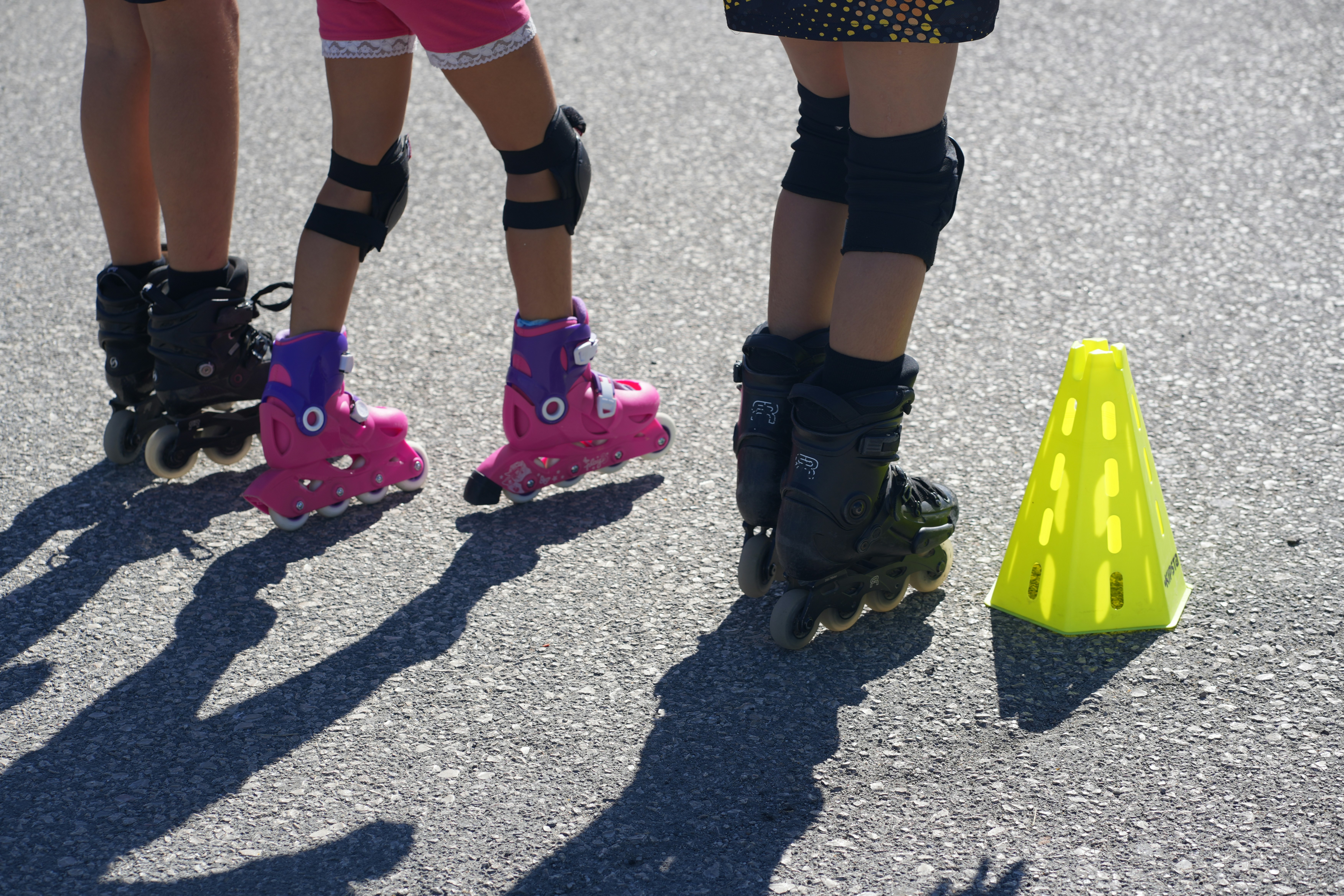 A couple of people riding roller skates next to a cone