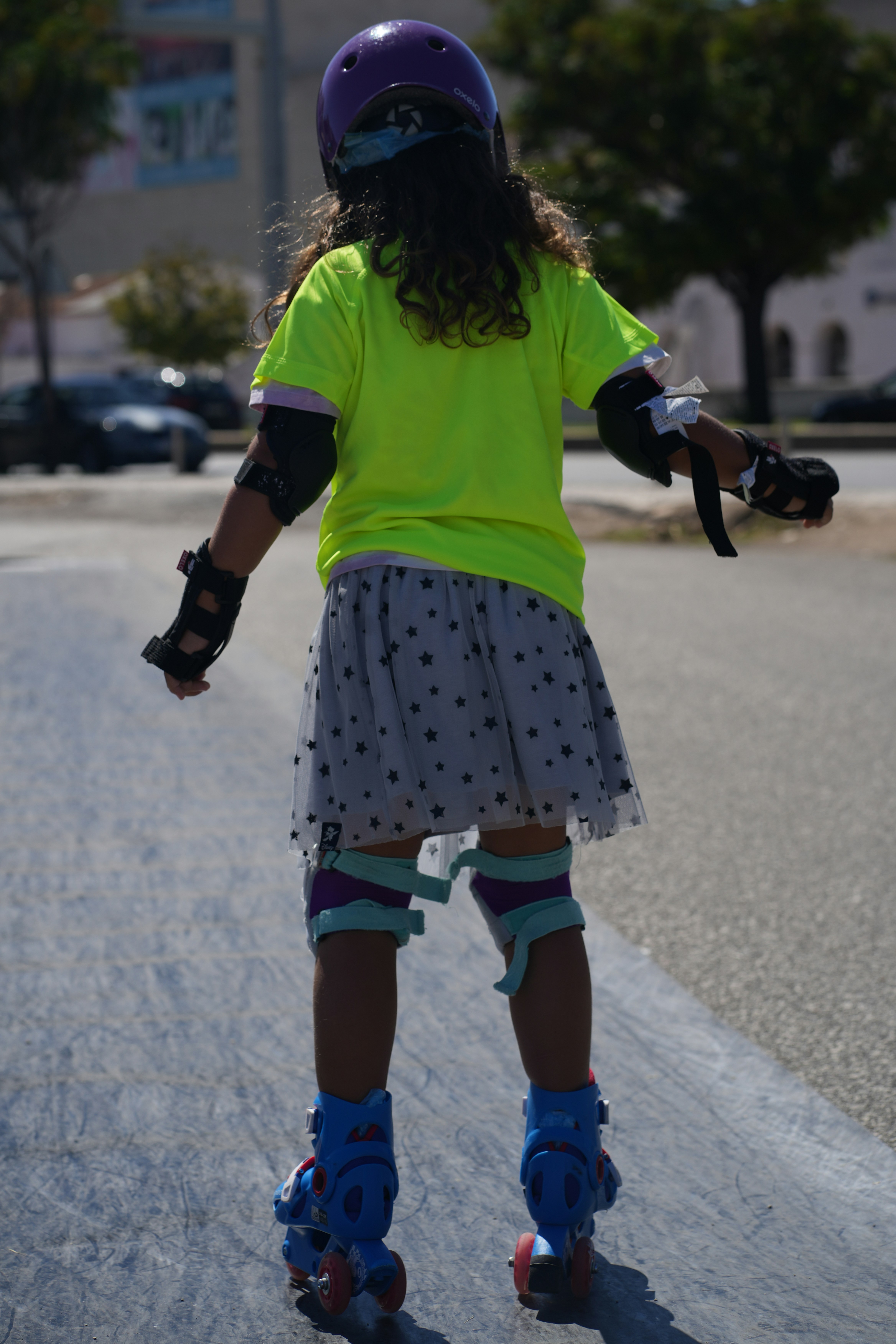 A little girl riding a skateboard down a street