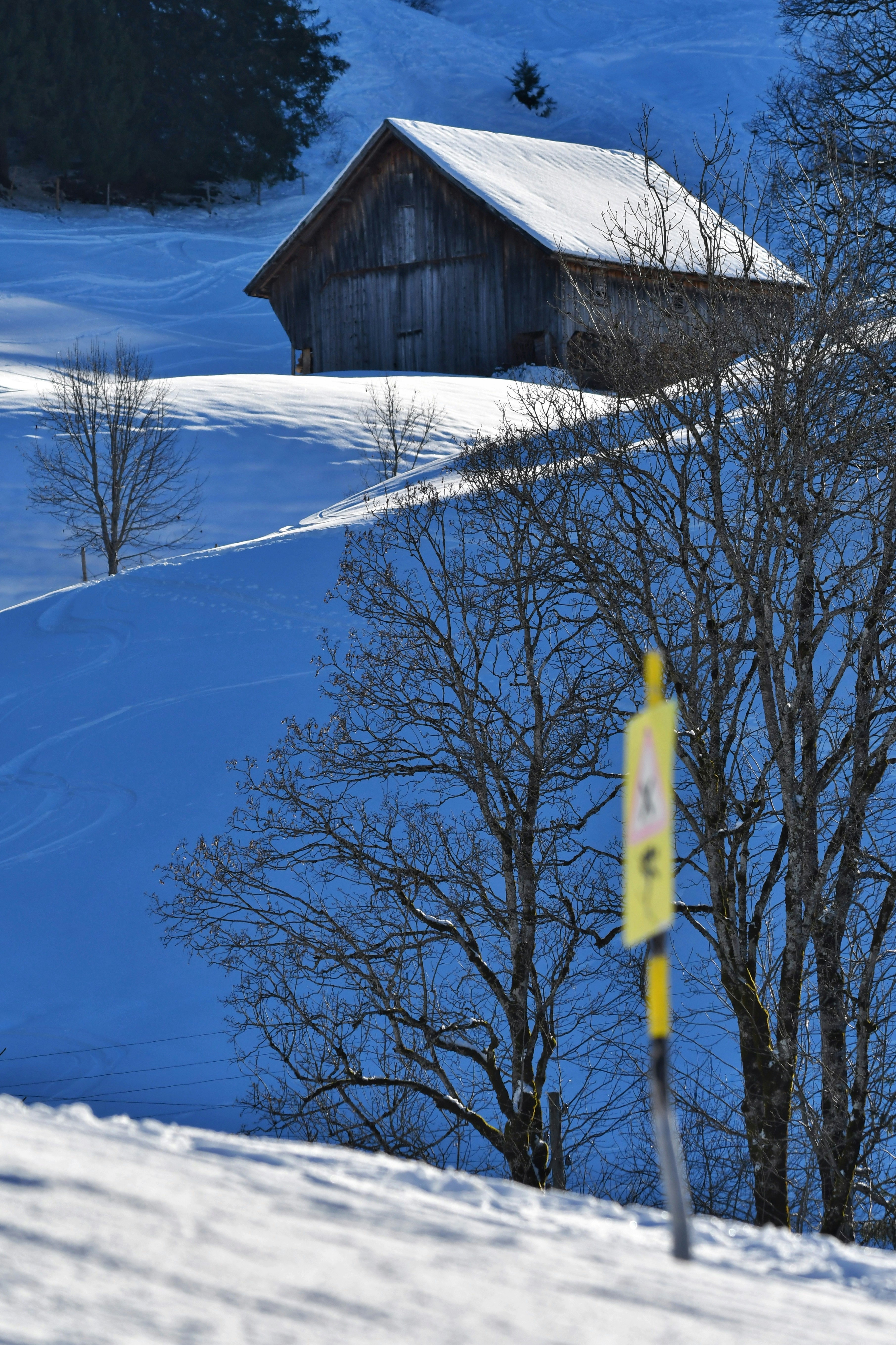 A snow covered hill with a barn in the distance
