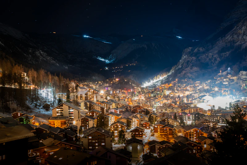 The car-free village of Zermatt lit up at night below the dark silhouette of the Matterhorn