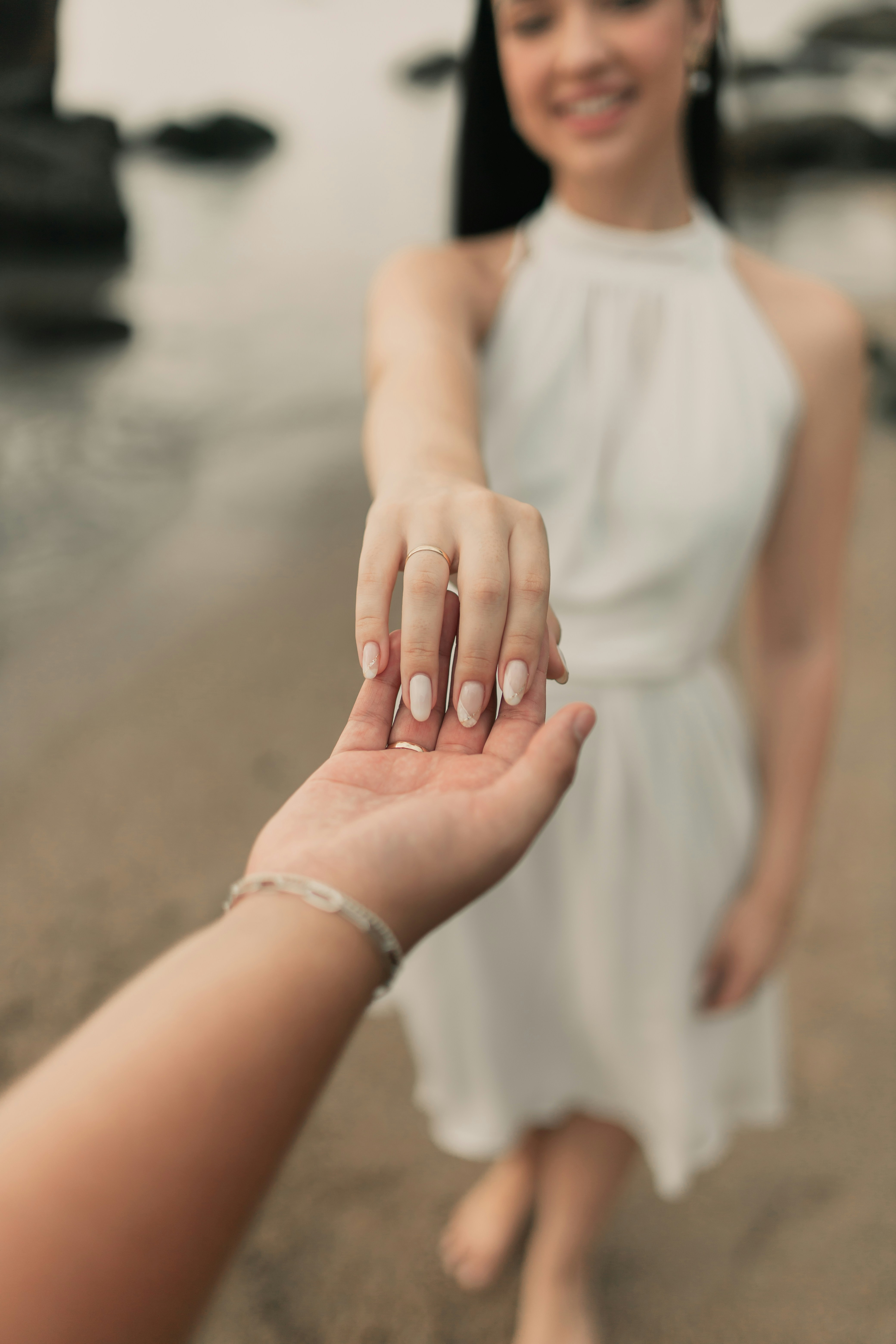 A woman holding the hand of a man on the beach