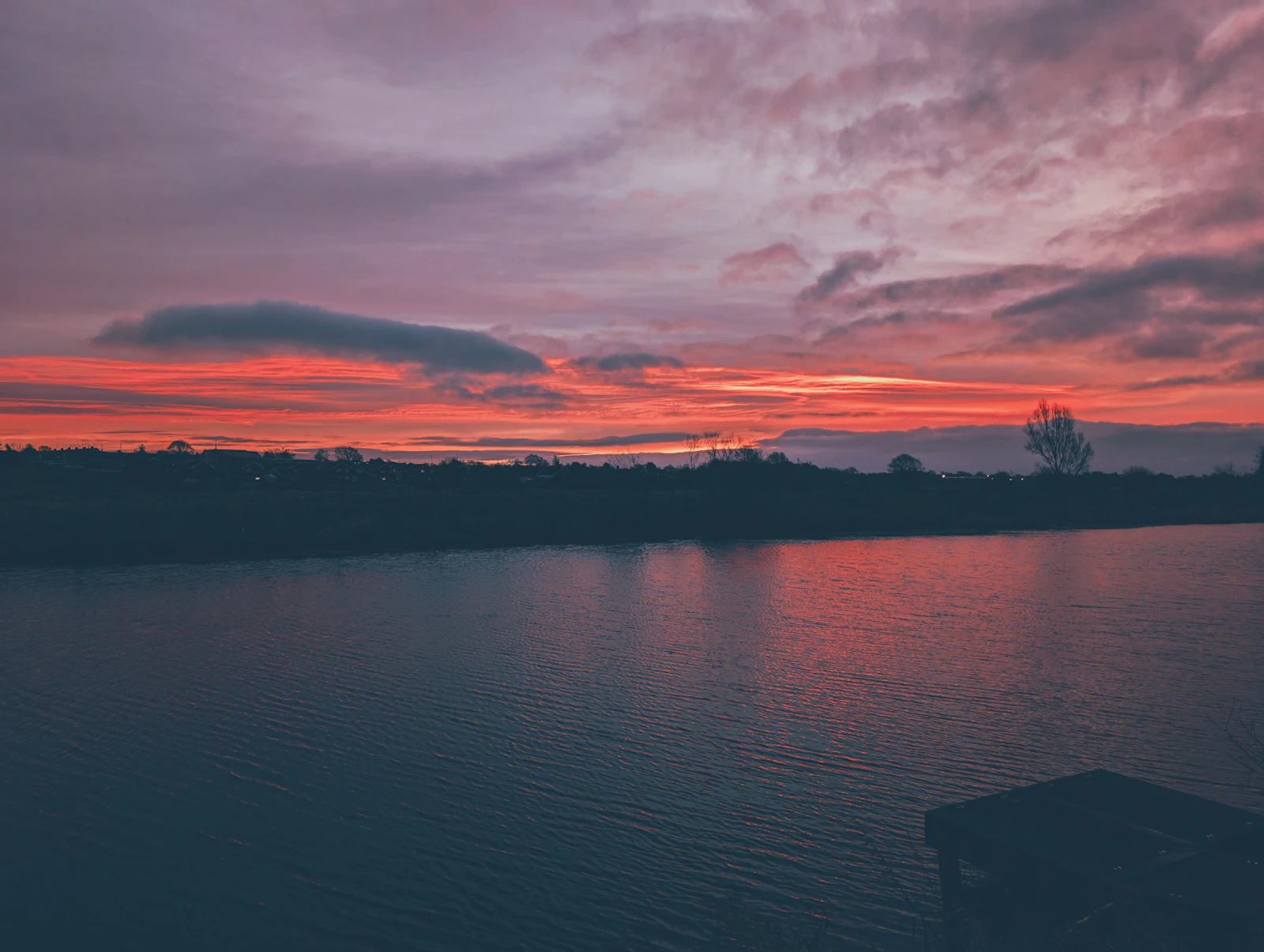 A wooden dock at sunset over calm lake water