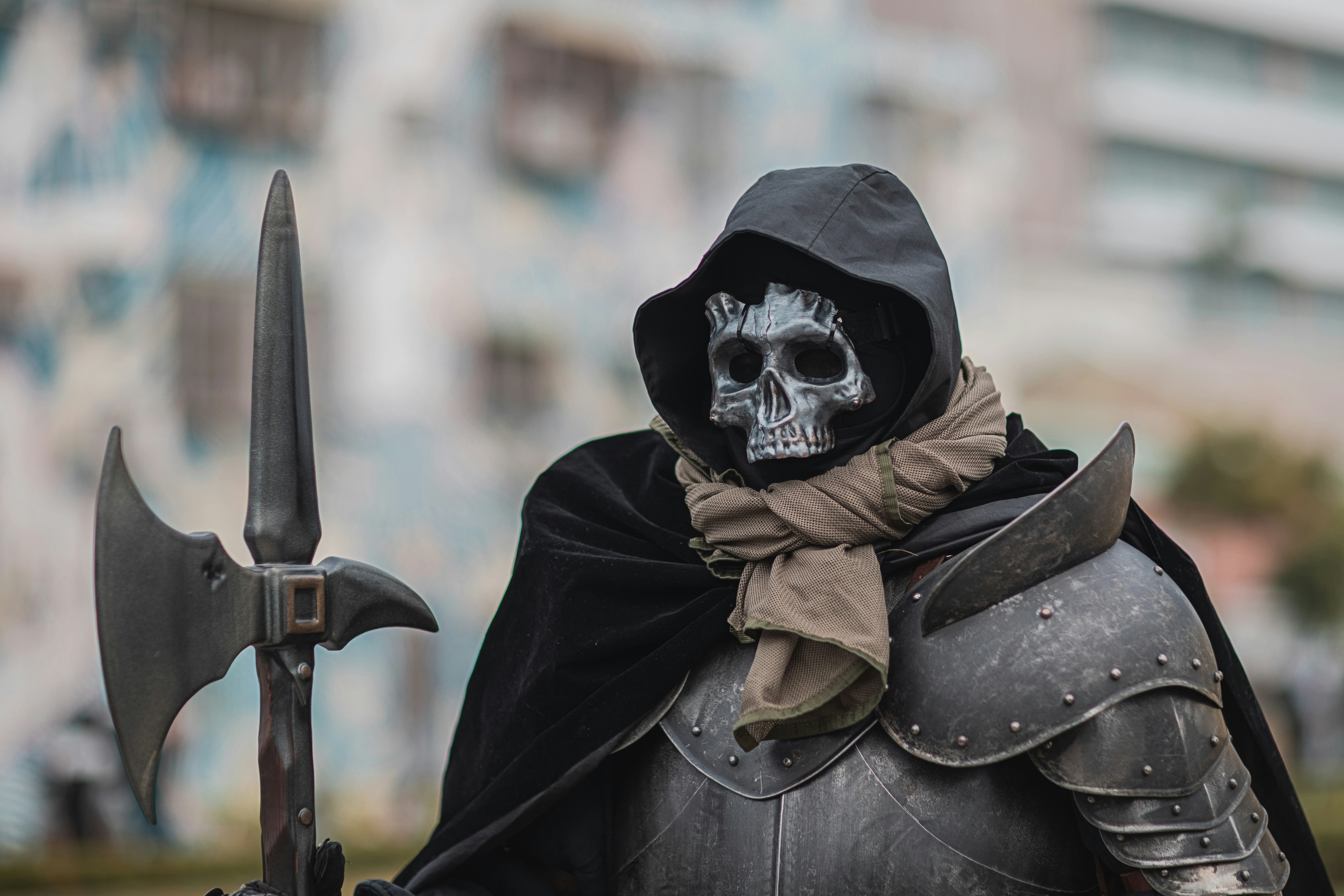 A man dressed in a black outfit with a skull on his head and a sword