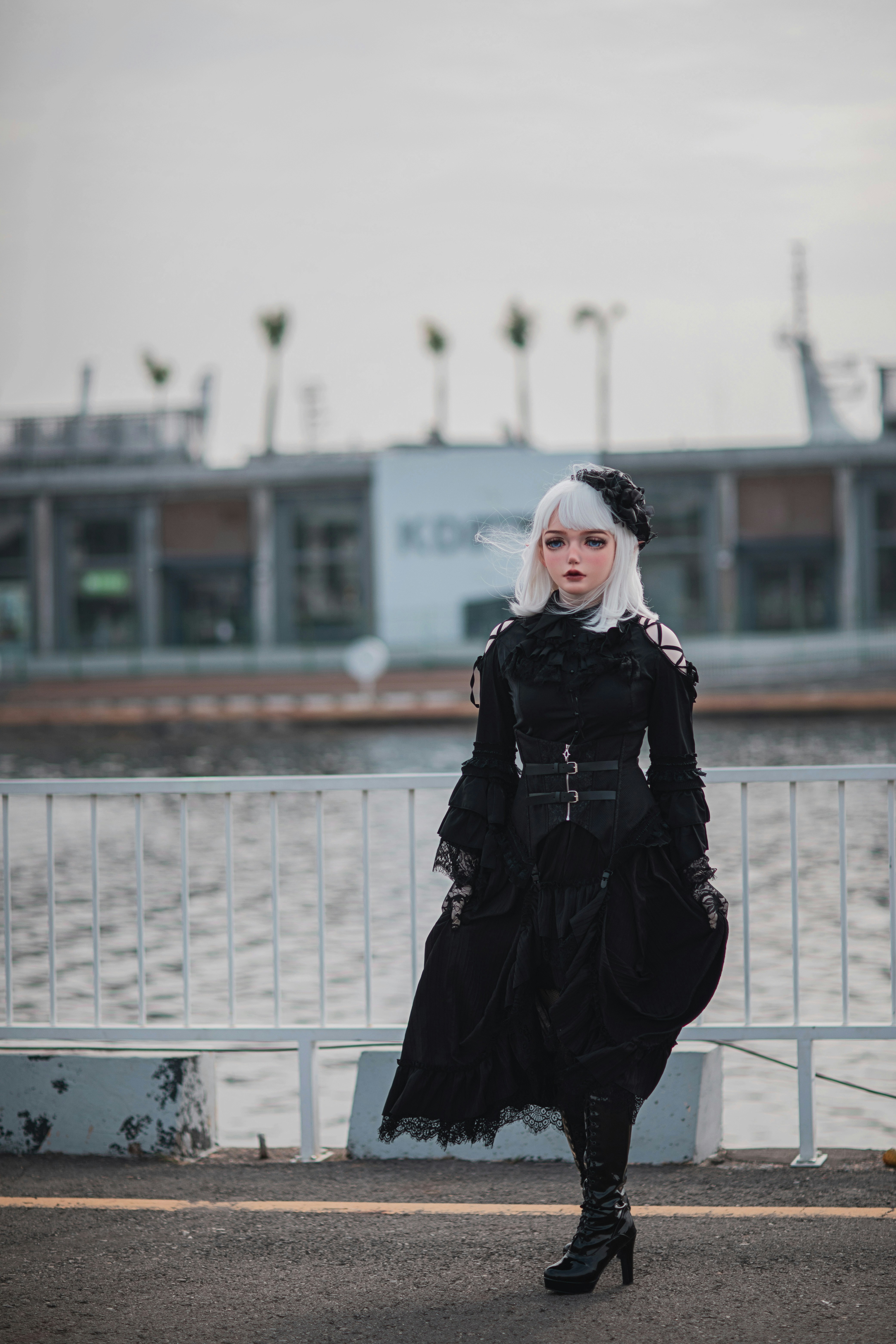 A woman in a black dress is standing by the water