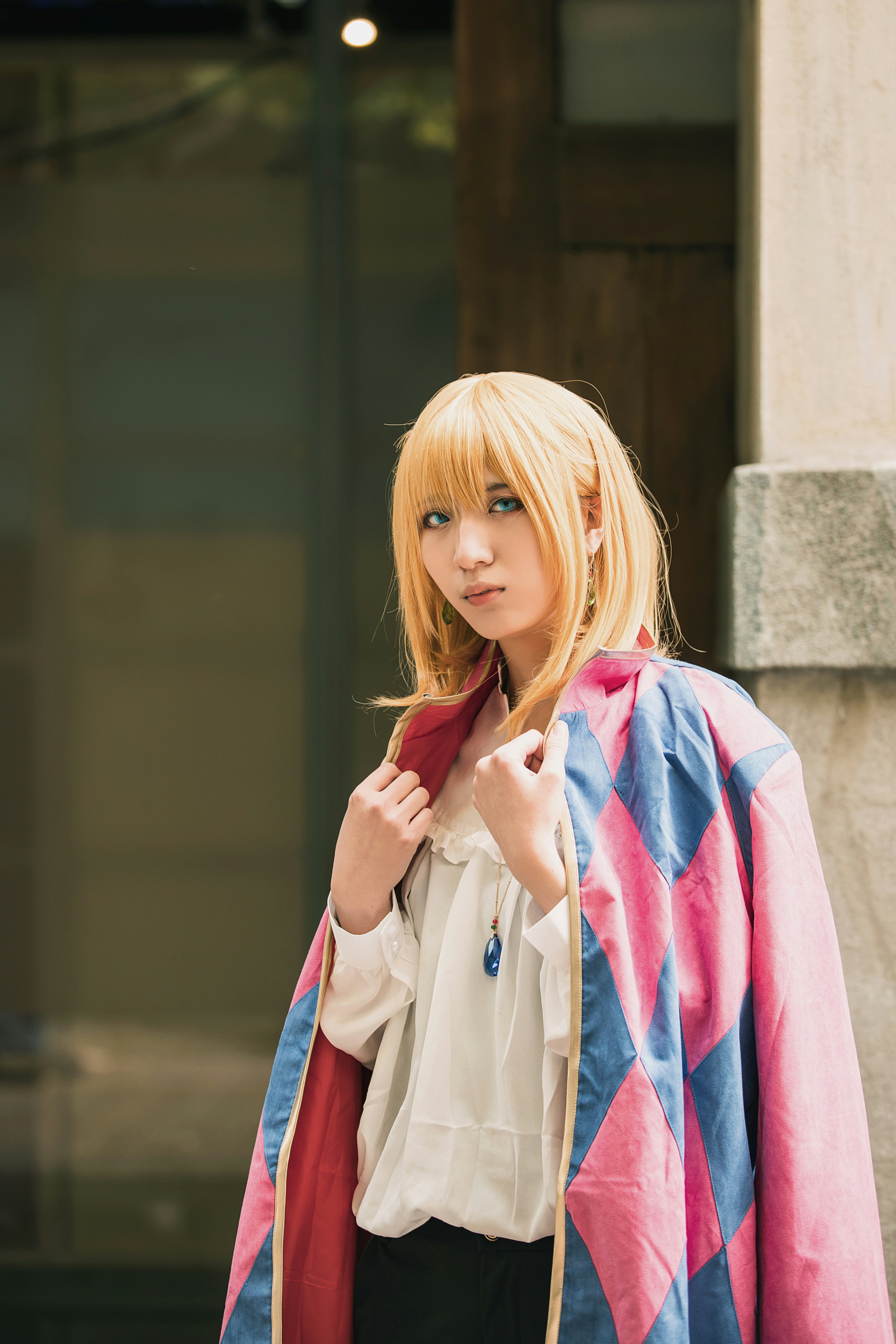 A woman with blonde hair wearing a pink and blue jacket