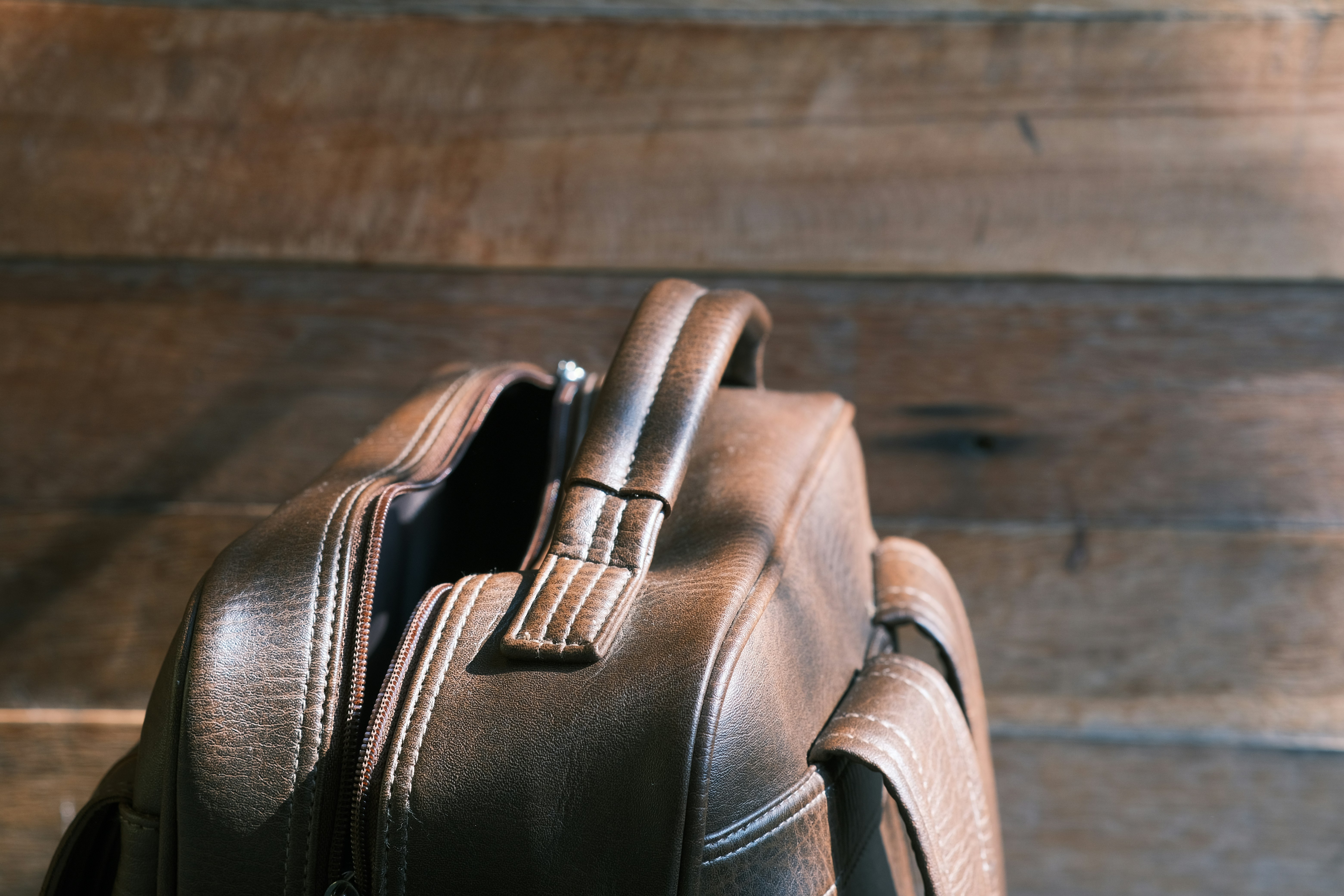 A brown leather backpack sitting on top of a wooden floor