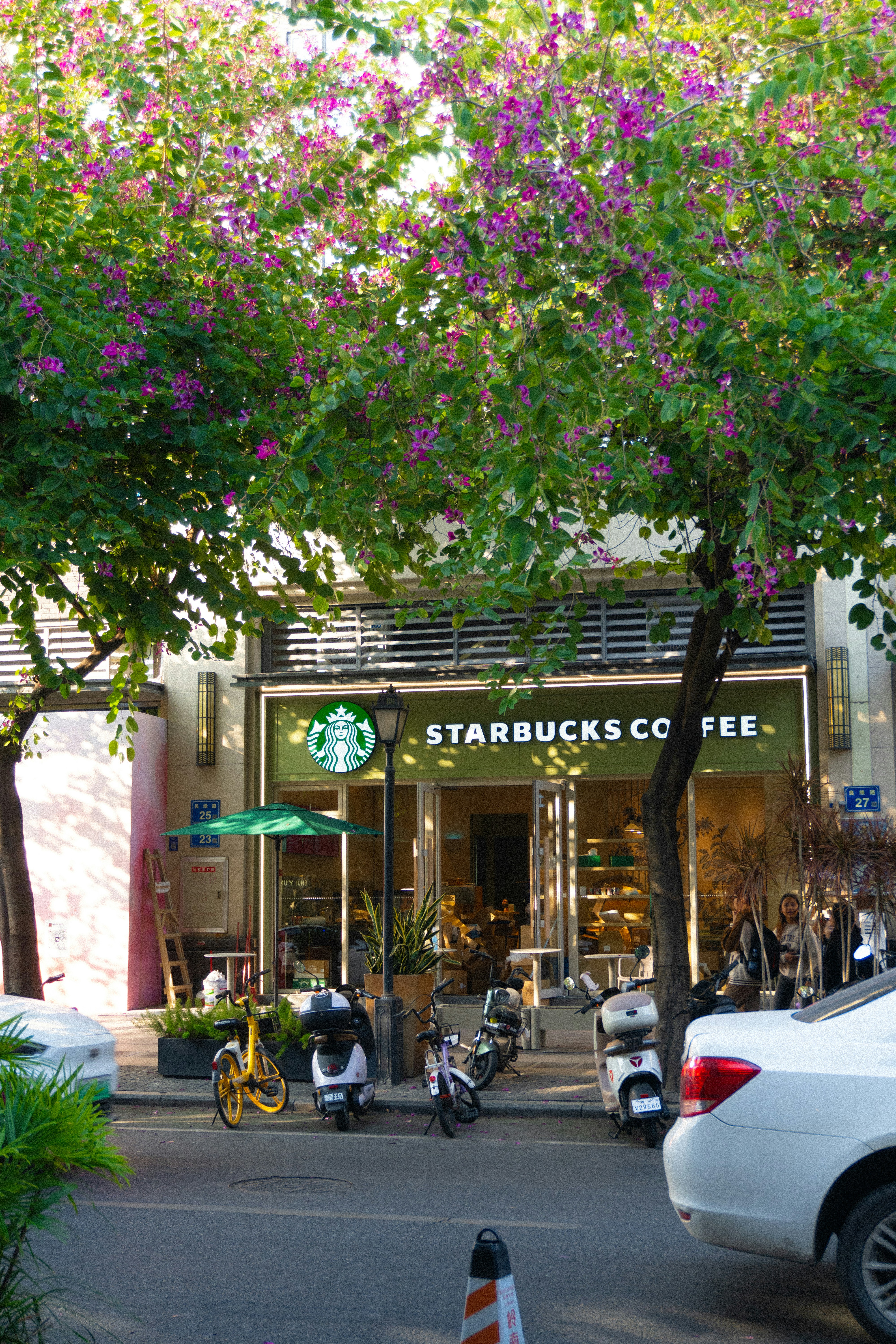 A white car driving down a street next to a tall building