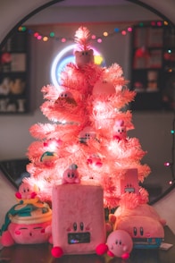 A pink christmas tree with a bunch of small toys around it