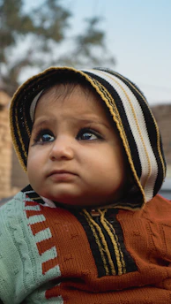 A small child wearing a sweater and a hat