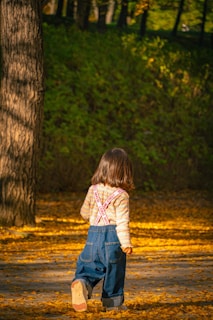 A little girl standing in the woods with a frisbee