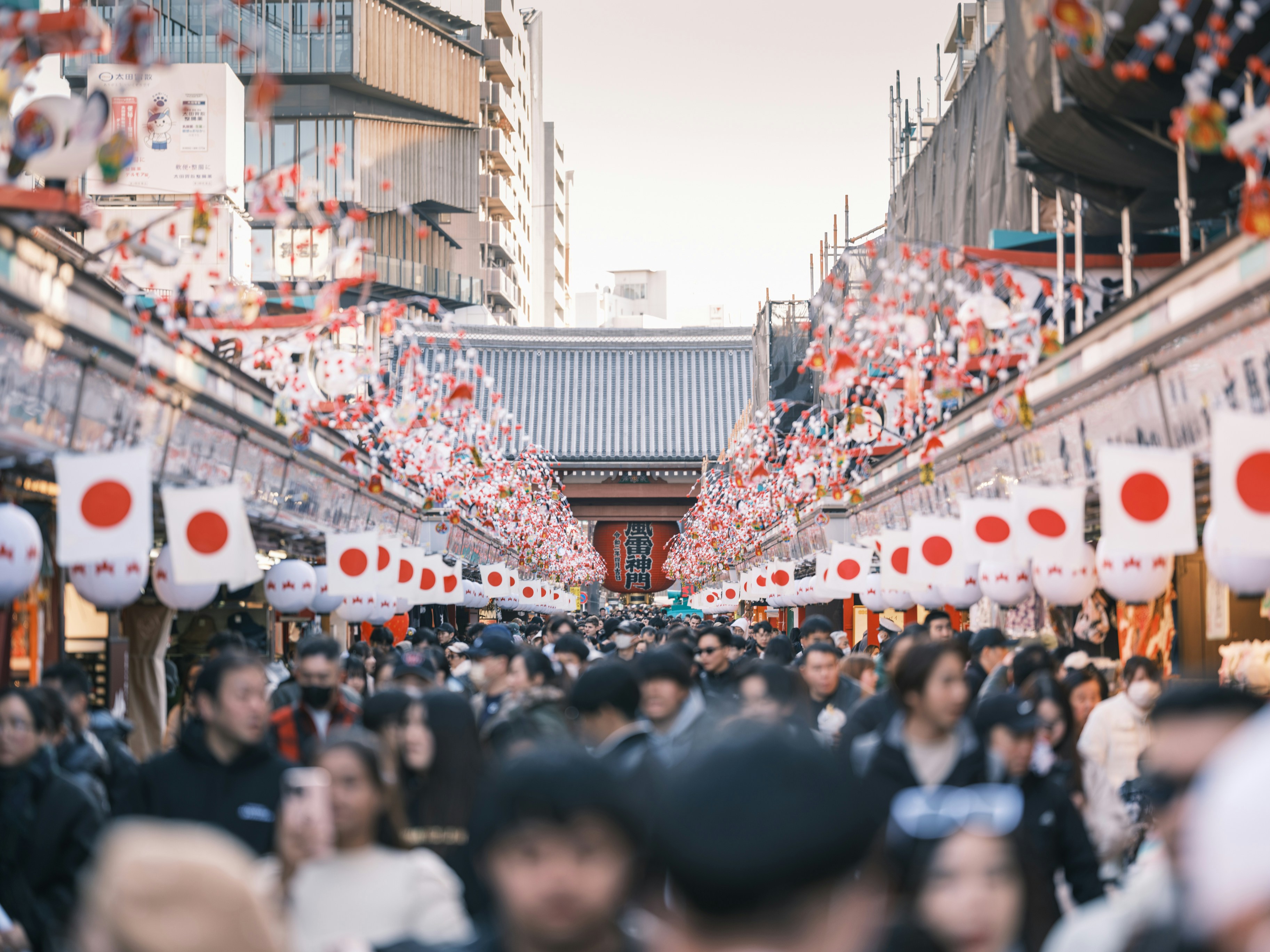 A crowd of people walking down a street next to tall buildings