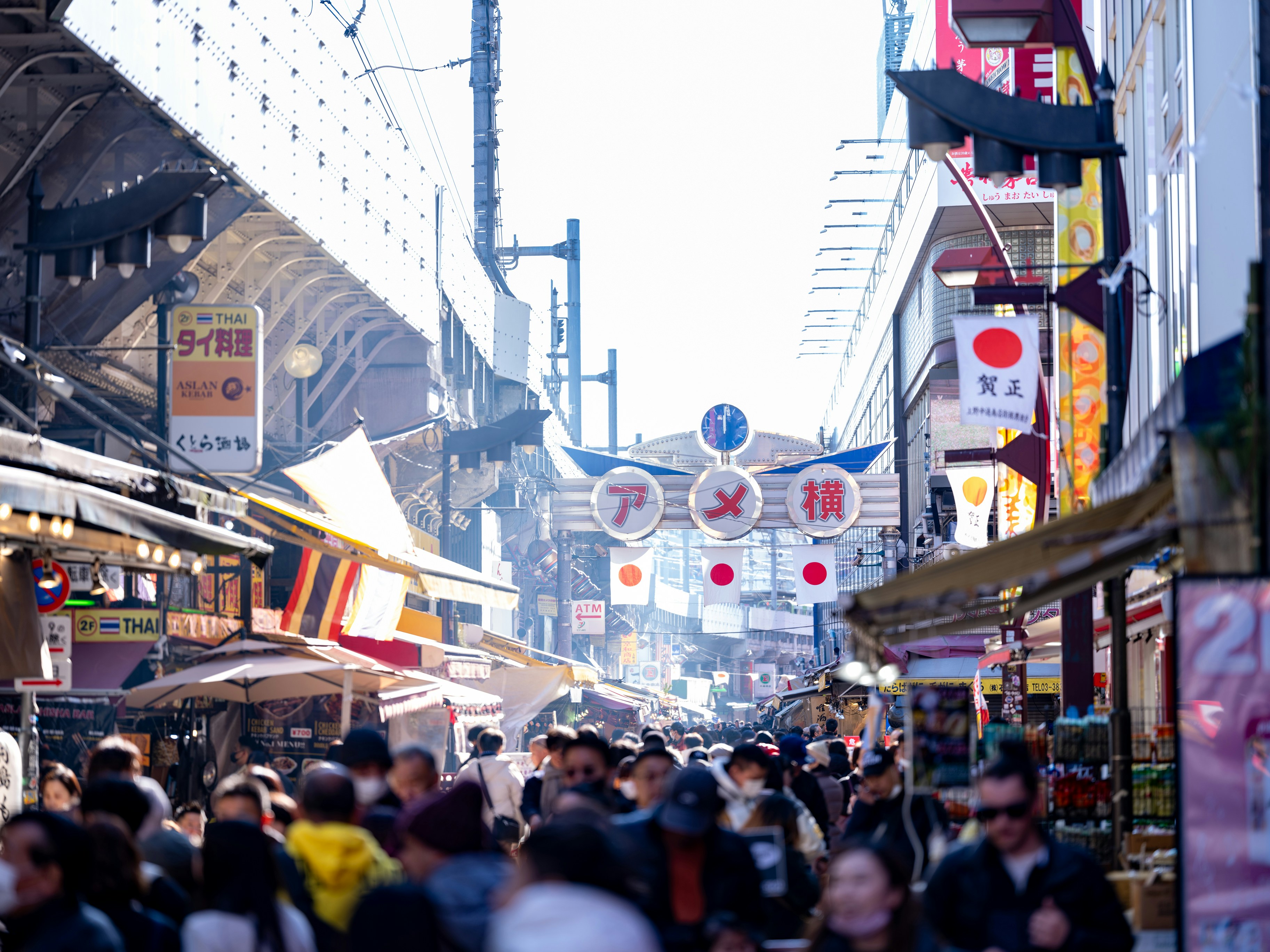 A crowd of people walking down a street next to tall buildings