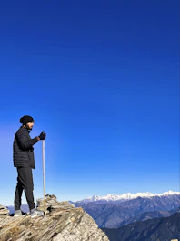 A man standing on top of a mountain holding a ski pole