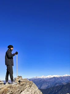A man standing on top of a mountain holding a ski pole
