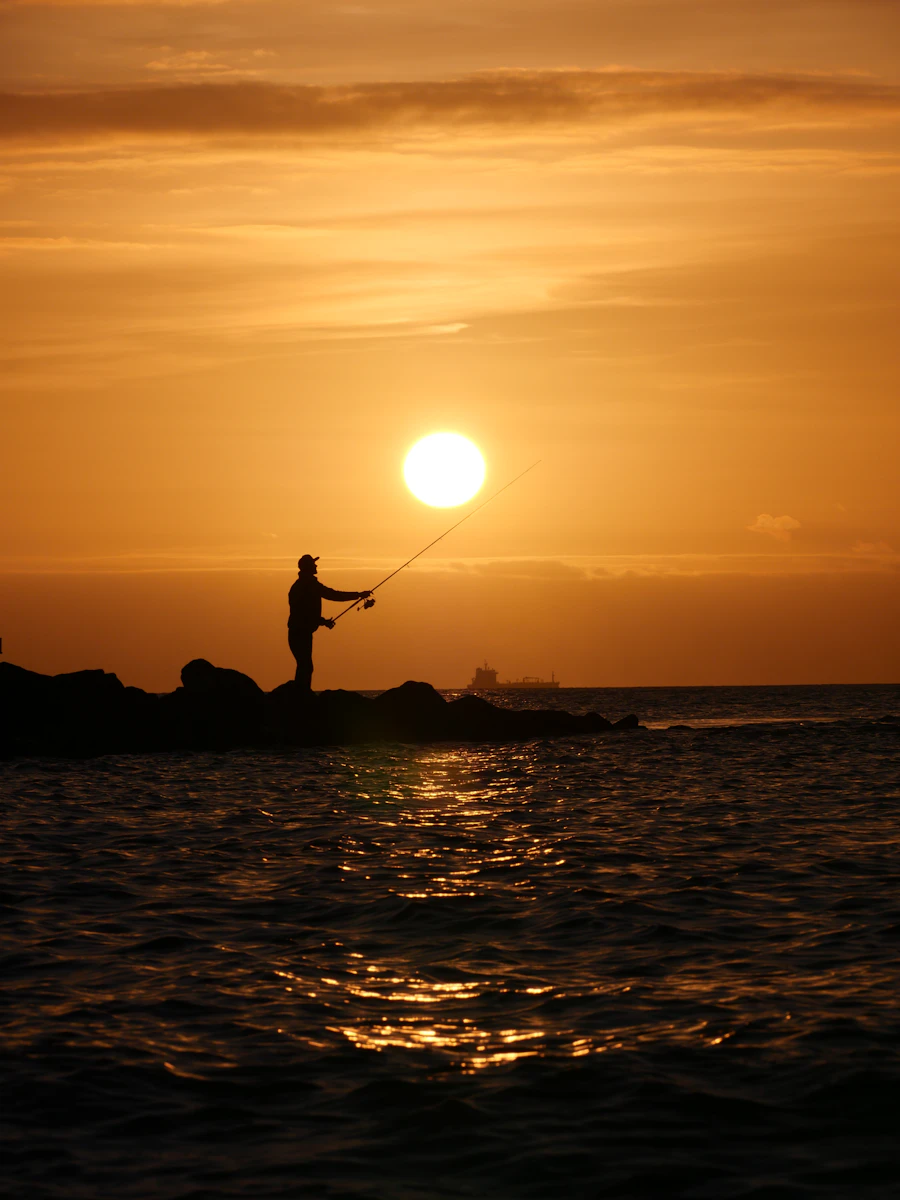 Pescador na beira da água ao entardecer