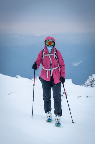 A woman in a pink jacket skiing on a mountain