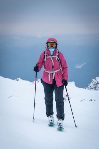 A woman in a pink jacket skiing on a mountain