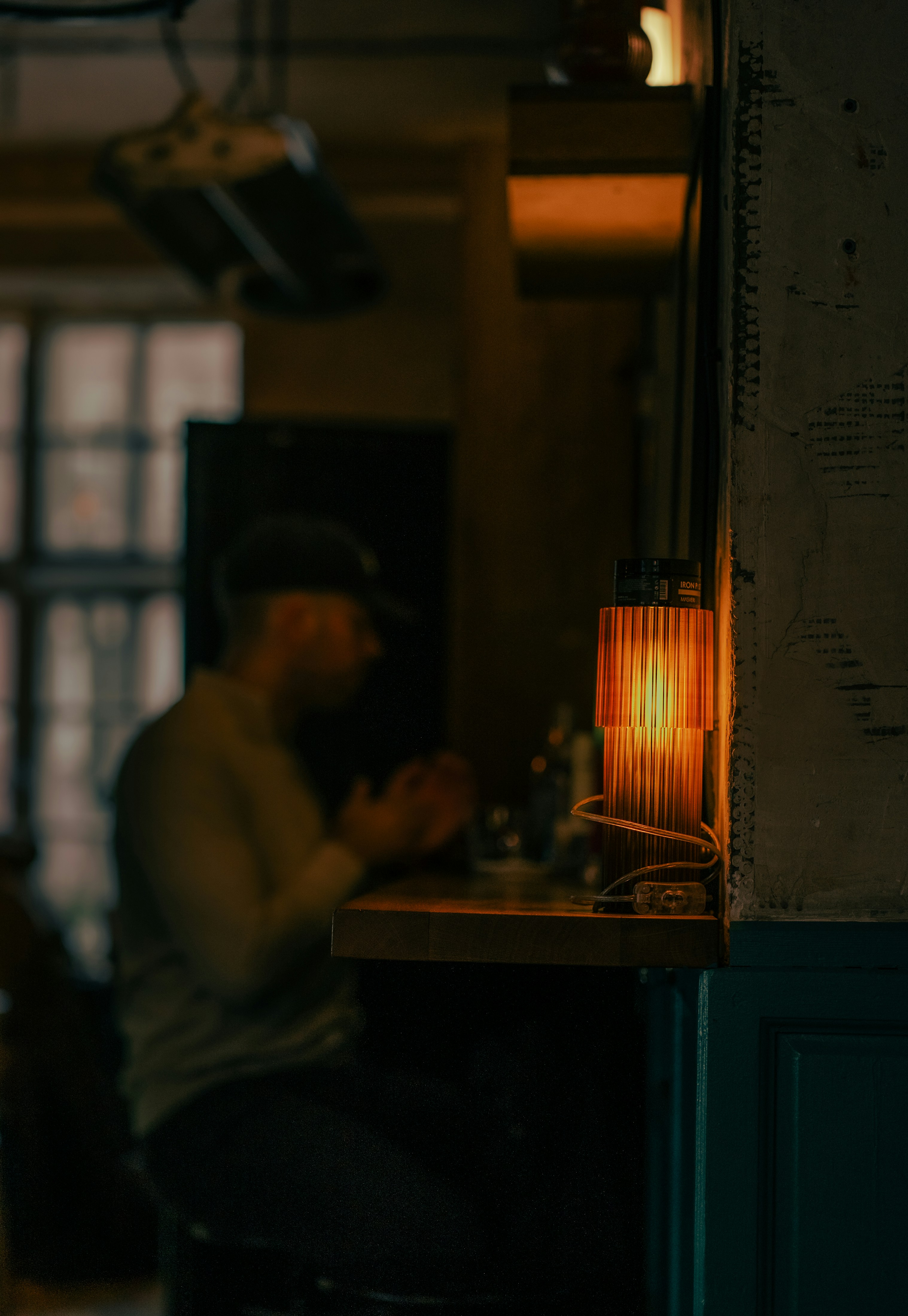 A person sitting at a table with a lamp on it