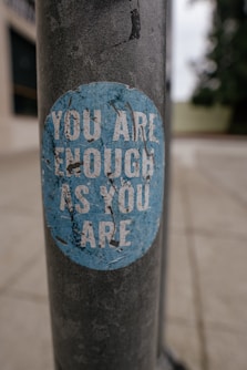 A sticker on a pole that says you are enough as you are