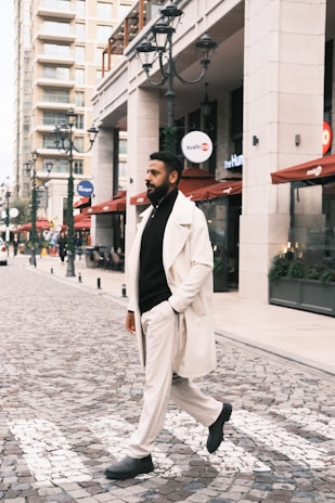 A man in a white coat walking down a street