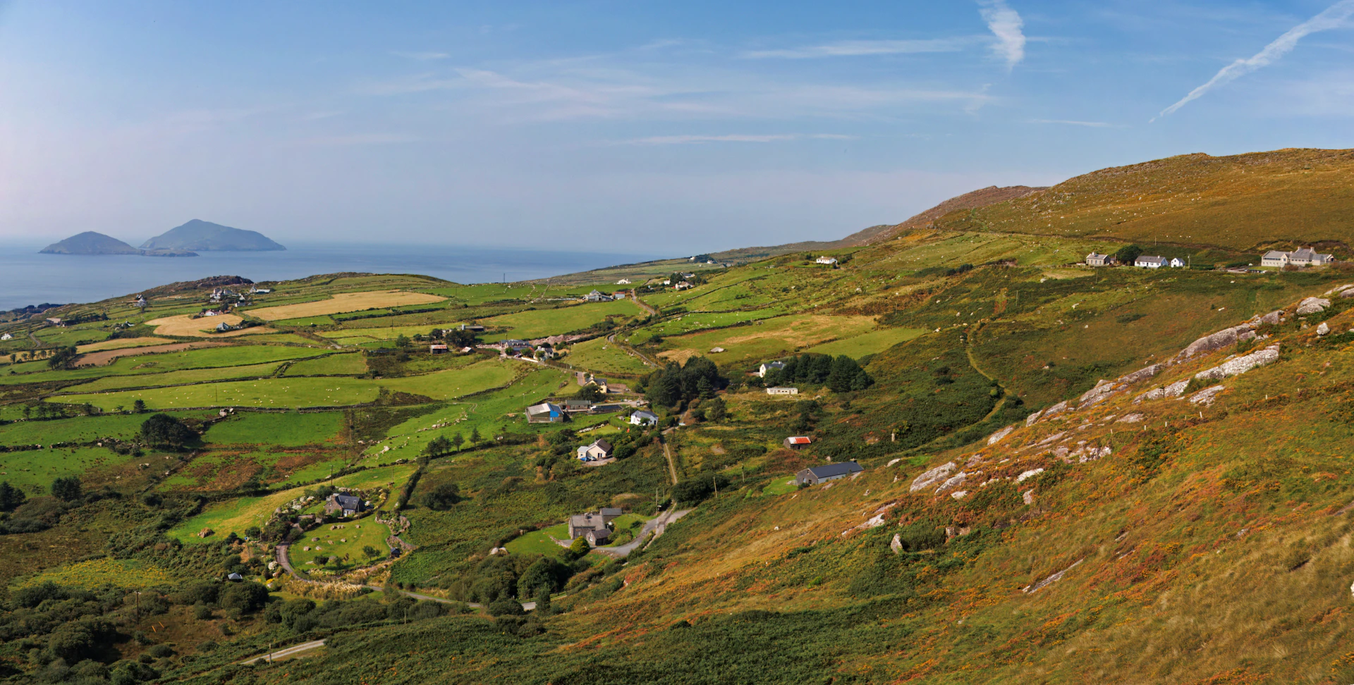 A scenic view of a grassy hill with a body of water in the distance