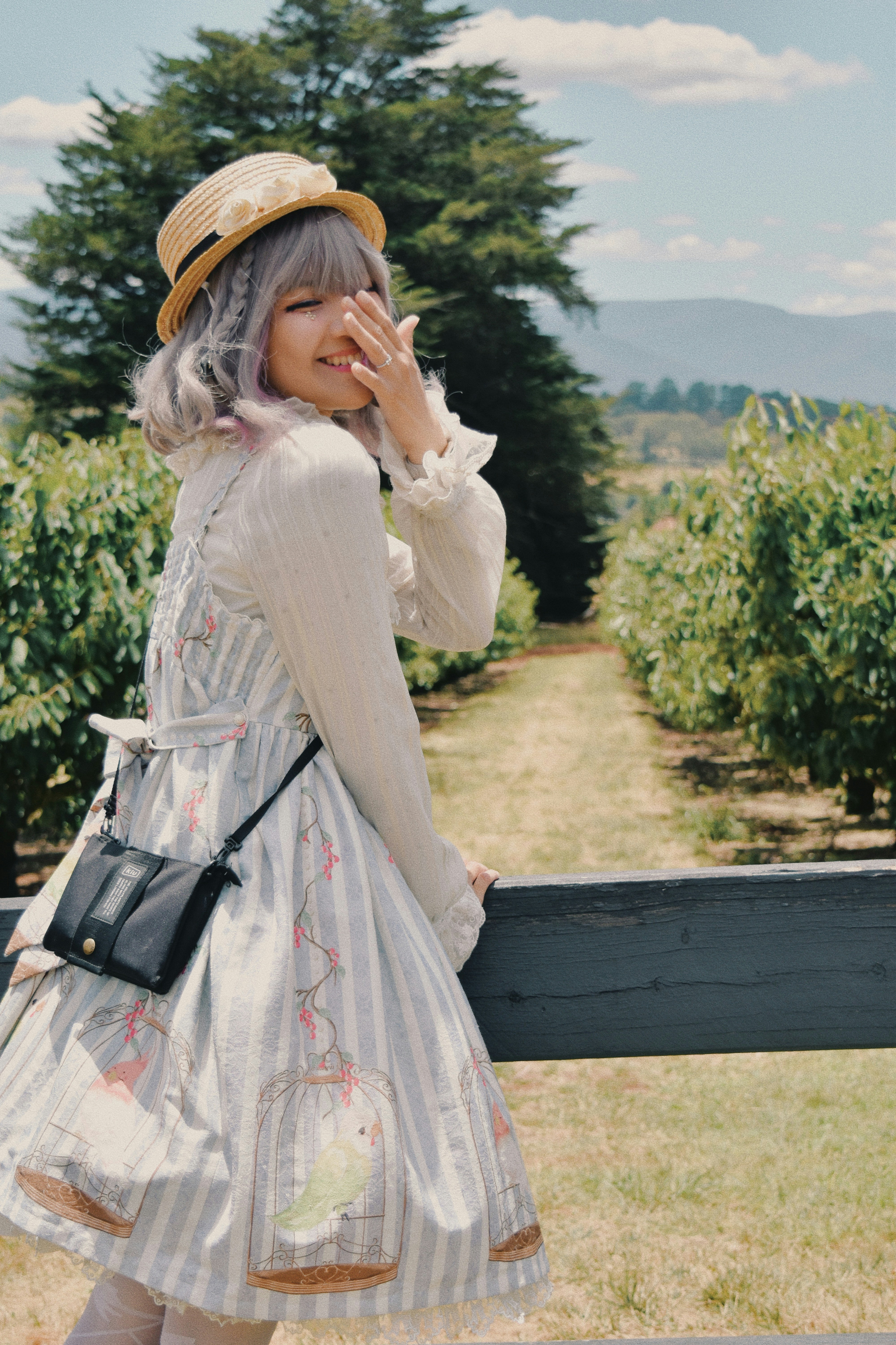 A woman standing next to a wooden fence